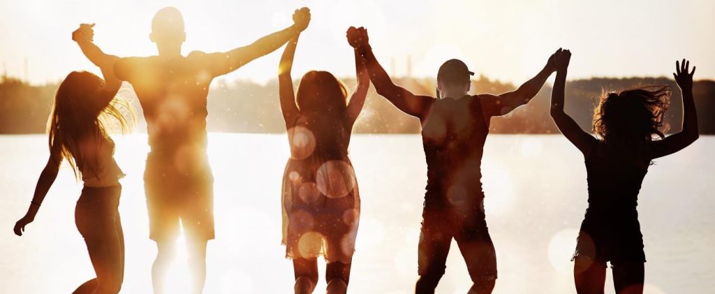 happy people with hands in air on beach